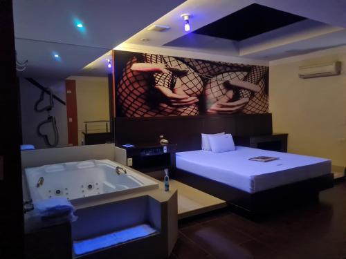 a room with a bath tub and a bed and a painting at Impulse Motel in São Bernardo do Campo