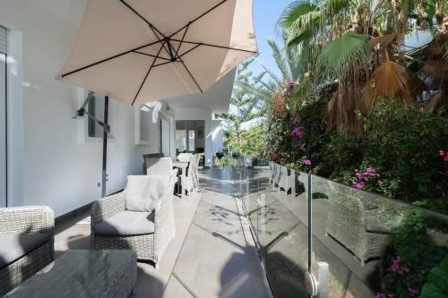 a patio with chairs and an umbrella and plants at Résidence Luxe avec Plage Privée in Bouznika