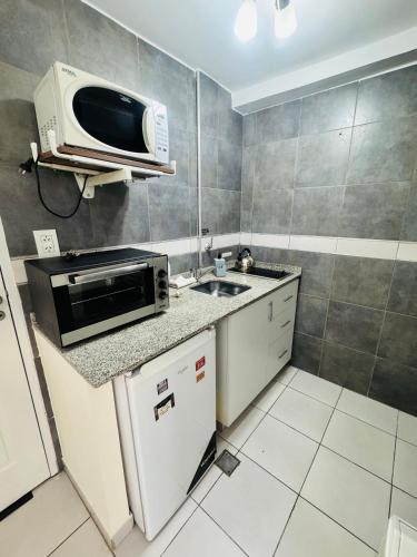 a small kitchen with a microwave and a sink at ApartSur Santa Fe in Santa Fe