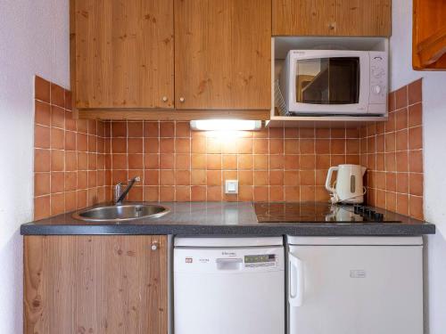 une petite cuisine avec un évier et un micro-ondes dans l'établissement Charmant 2 pièces 5 pers, proche centre, pistes et luge, avec balcon sud, Wi-Fi et casier à ski - FR-1-314-263, à Morzine