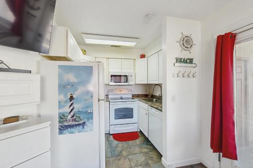 a kitchen with white cabinets and a red rug at Paradise Cove in Panama City Beach