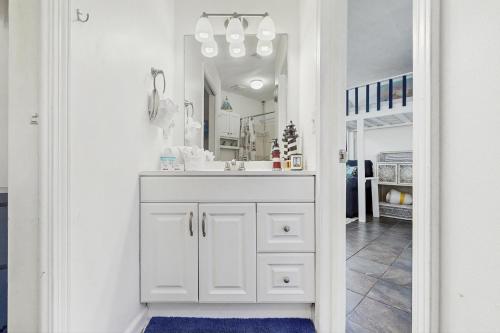 a white bathroom with a sink and a mirror at Paradise Cove in Panama City Beach