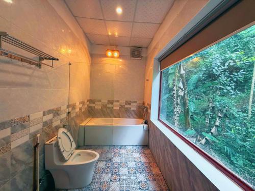 a bathroom with a toilet and a tub and a window at Chinh Thu Garden Retreat in Ninh Binh