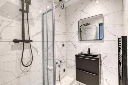 La salle de bains blanche est pourvue d'une douche et d'un miroir. dans l'établissement Studio Annemasse tout confort, à Annemasse