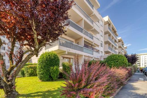 un immeuble d'appartements avec des buissons et des fleurs devant lui dans l'établissement Studio Annemasse tout confort, à Annemasse