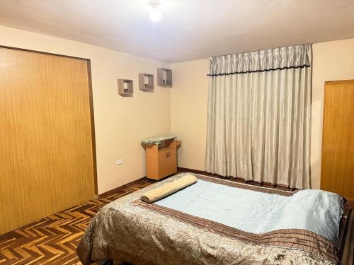 a bedroom with a bed and a large window at Amplio departamento con jacuzzi in Puno