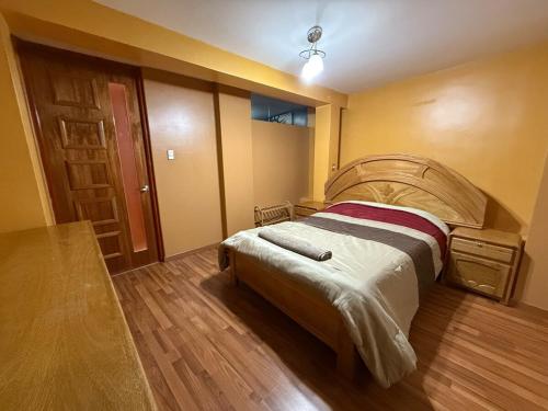 a bedroom with a bed and a wooden floor at Amplio departamento con jacuzzi in Puno
