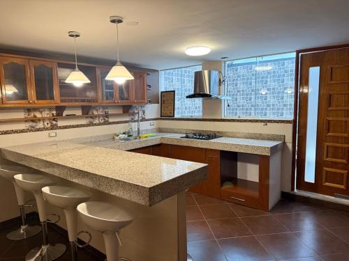 a kitchen with a large island with bar stools at Amplio departamento con jacuzzi in Puno