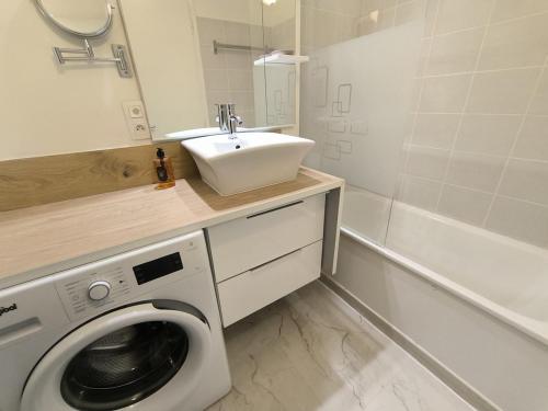 une salle de bain avec une machine à laver et un lavabo dans l'établissement Appartement Mimizan Plage, à Mimizan-Plage
