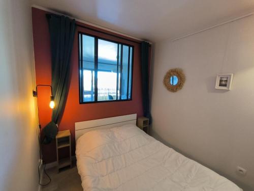 une petite chambre avec un lit et une fenêtre dans l'établissement Appartement Mimizan Plage, à Mimizan-Plage