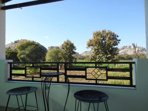 a balcony with two stools and a view of a field at Jawai Leopard Villa in Bijāpur