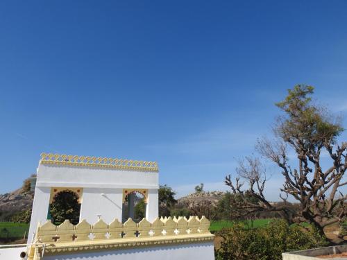 a white house with a fence and trees in the background at Jawai Leopard Villa in Bijāpur