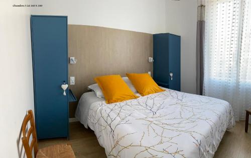 une chambre avec un lit avec des oreillers bleus et jaunes dans l'établissement Villa Les Lauriers, à Les Sables-dʼOlonne