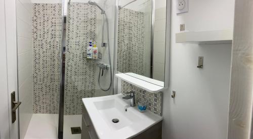 une salle de bain blanche avec un lavabo et une douche dans l'établissement Villa Les Lauriers, à Les Sables-dʼOlonne