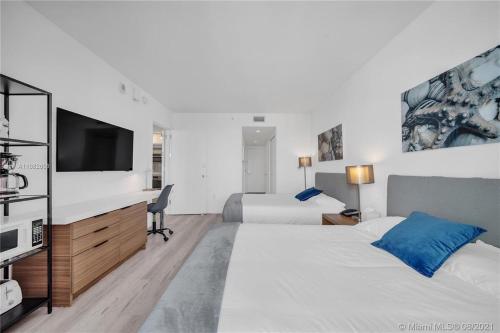 een slaapkamer met twee bedden en een flatscreen-tv bij Beachfront Studio, 2 Full Beds, Dream View 2804 in Hallandale Beach