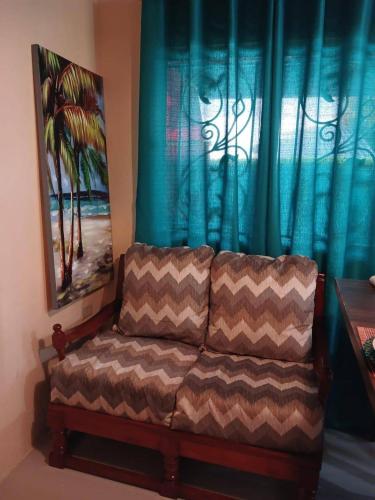 a couch sitting in front of a window with blue curtains at Casa Cicada at 18 Cicada Drive in Jerningham Junction