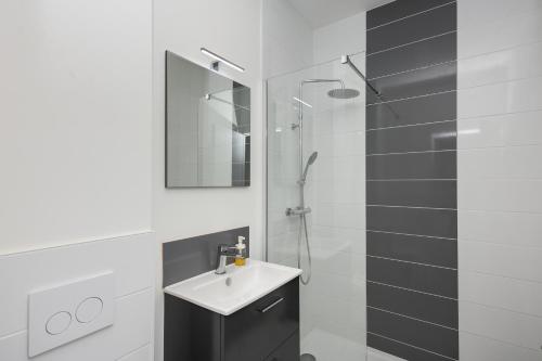 une salle de bain blanche avec un lavabo et une douche dans l'établissement Le Triomphant, à Brest