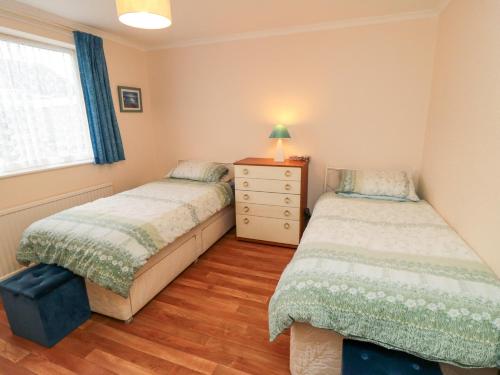 a bedroom with two beds and a dresser and a window at Sycamore in Filey