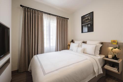 a bedroom with a large white bed and a window at 2BR Cozy City View CBD Sudirman Park Apartment, Luxury & Chic Design in Jakarta