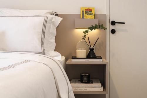 a bedroom with a bed and a nightstand with a plant and books at 2BR Cozy City View CBD Sudirman Park Apartment, Luxury & Chic Design in Jakarta