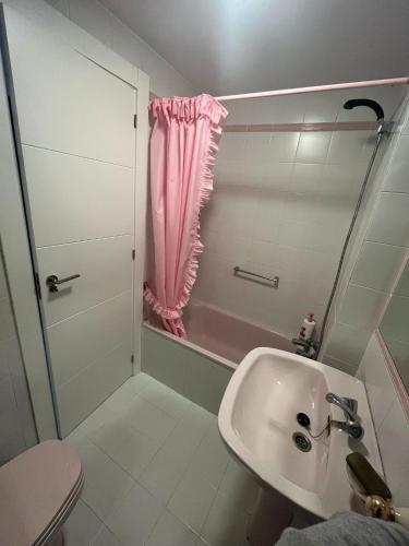 a bathroom with a sink and a shower with a pink curtain at El buen sol de la manga in La Manga del Mar Menor