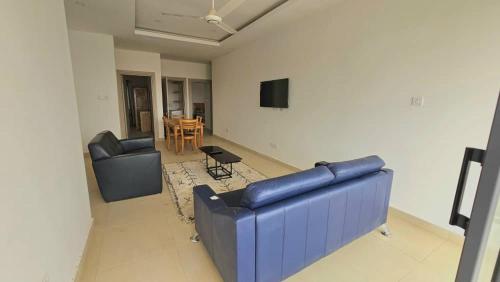 Una sala de estar con un sofá azul y una mesa. en Golden Sands Villa, en Gunjur