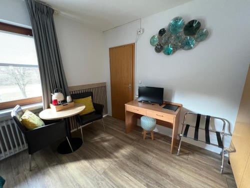 a room with a desk with a computer and a table at Am Obersee Hotel in Simmerath