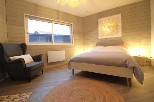 a bedroom with a bed and a chair and a window at Gite, Maison Chaleureuse in Saint-Léonard