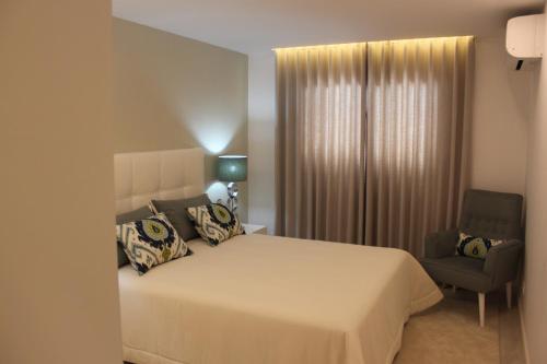 a bedroom with a large white bed and a chair at Apartamento Morning Cascade in Carvoeiro