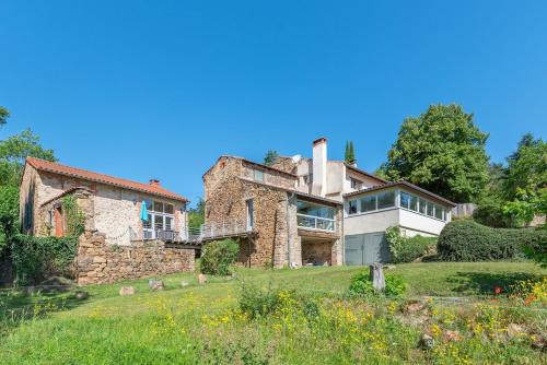 a large stone house on a grassy field at Gîte atypique Nature La Cabane in Vieille-Brioude