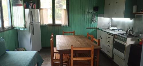 a kitchen with a wooden table with chairs and a refrigerator at Sol de Sauce in Balneario Sauce Grande