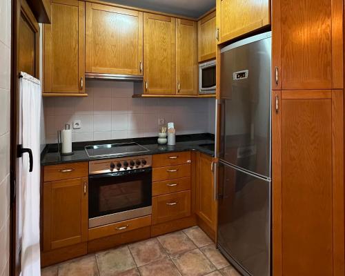 a kitchen with wooden cabinets and a stainless steel refrigerator at Las Casucas de Remoña in Espinama
