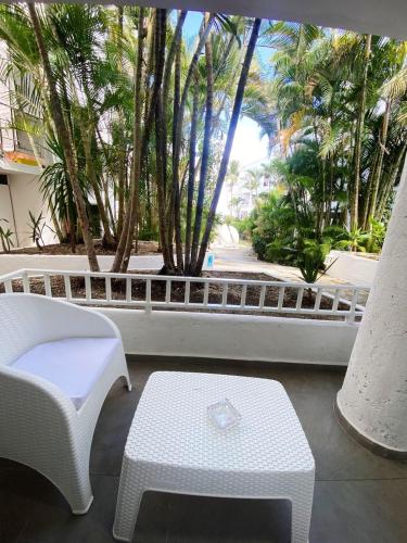 a patio with a table and a bench and palm trees at Cabarete Kite Beach Rooms & Condos in Cabarete