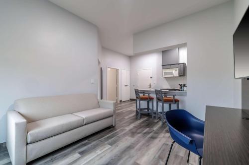a living room with a couch and a kitchen at Studio 6 Suites Brenham, TX in Brenham