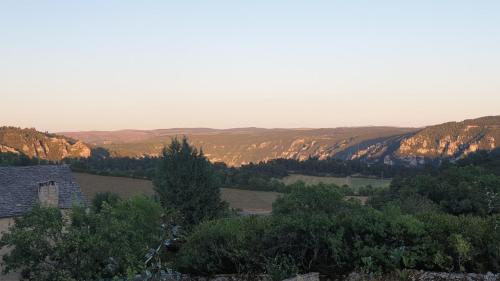 - une vue sur une vallée avec une maison et des arbres dans l'établissement Maison en pierre Gorges du Tarn, à Saint-Georges-de-Lévéjac