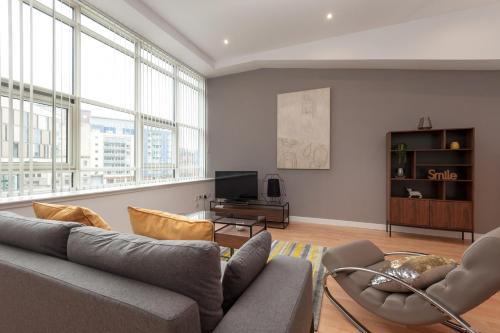 a living room with a couch and chairs and windows at Glasgow City Flats - Merchant City in Glasgow
