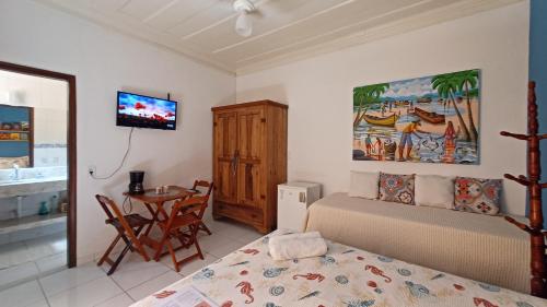 a bedroom with a bed and a table and a tv at Suítes Canto do Pontal in Paraty
