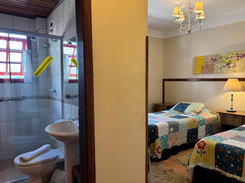 a bathroom with a shower and a toilet and a sink at Pousada Benevento in Campos do Jordão