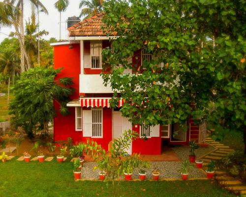 a red house with a tree in front of it at Philosopher's Stone in Varkala