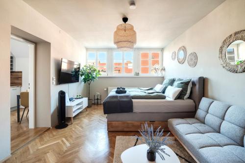 a living room with a couch and a tv at Boho Design Studio - Historic City Center with Free Parking & AirCon by HERO HOMES in Graz