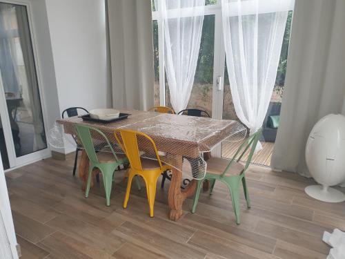 une table à manger entourée de chaises colorées. dans l'établissement grand appartement CALVI, à Calvi