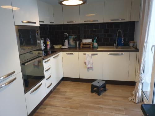 une cuisine avec des armoires blanches et un plancher en bois dans l'établissement grand appartement CALVI, à Calvi