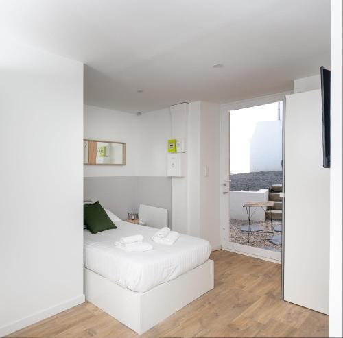 - une chambre blanche avec un lit et une porte coulissante en verre dans l'établissement Dame Blanche, à Brest