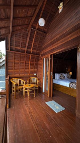 a bedroom with a bed and two chairs and a table at Sayong Wooden House in Ubud