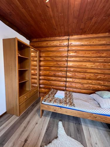 a bedroom with a bed and a wooden wall at Knieja u Andrzeja in Lutowiska