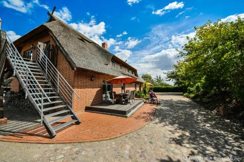 a house with a thatched roof and a patio at Dreiurtshof in Remplin