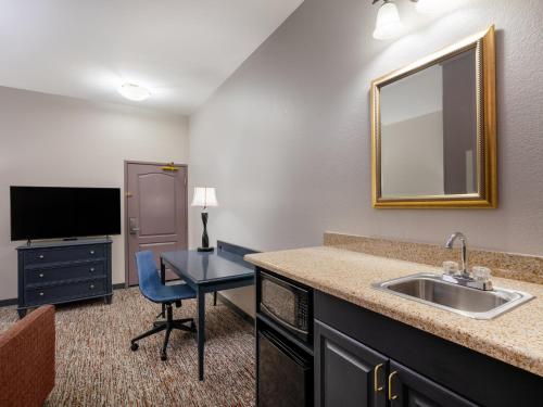 a bathroom with a sink and a desk with a mirror at Garner Hotel Gillette South by IHG in Gillette