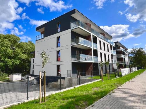 an apartment building with a fence in front of it at Apartamenty Klonova Park in Olecko