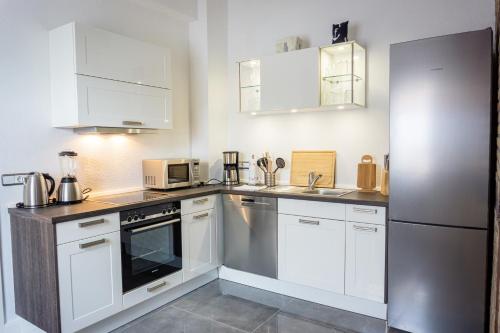 a kitchen with white cabinets and a stainless steel refrigerator at Mien Tied MITTENMANG in Heiligenhafen