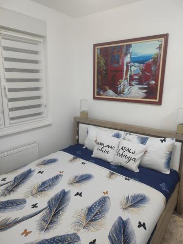 a bedroom with a bed with a blue and white comforter at Tri palme in Banja Koviljača